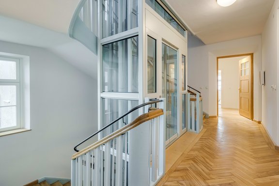 A modern glass elevator leads to the second floor