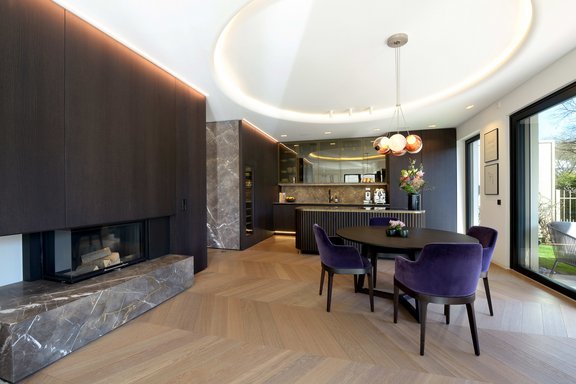 Natural stone, a fireplace, French herringbone parquet and a brilliant lighting concept convey luxurious flair