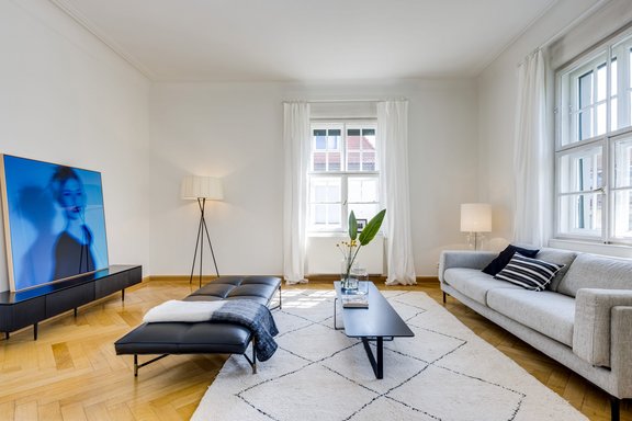 With muntin windows, ceiling stucco and herringbone parquet, the living room conveys fine old building charm